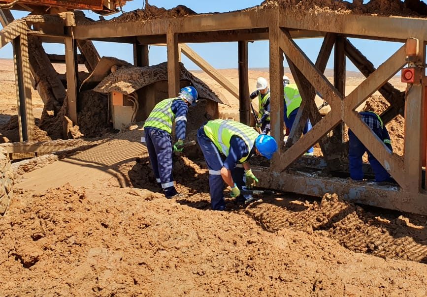 Crew cleaning beneath mining conveyors