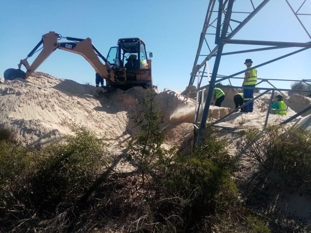 Excavator removing beach sand from a structure